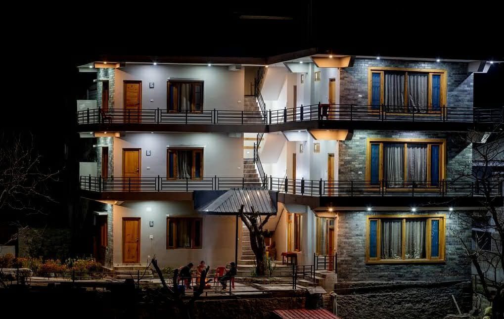 Un edificio de varios pisos con balcones, escaleras y una entrada bien iluminada.