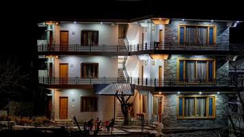 Un edificio de varios pisos con balcones, escaleras y una entrada bien iluminada.