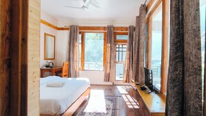 A bedroom with a bed, a desk, a chair, a window, and curtains. - Tirthan Grand Riverside  (Sainj)
