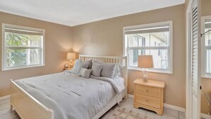 Ein Schlafzimmer mit Bett, Nachttischen und Fenstern.