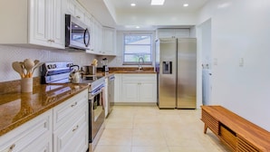 A modern kitchen with white cabinetry, stainless steel appliances, and a granite countertop. - Beautiful 3 2 Home in Pompano Beach - Close to Beach (Pompano Beach)