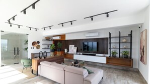 Una sala de estar moderna con un sofá, una mesa de centro y un televisor. Se observa una zona de cocina con una mesa de comedor y sillas.