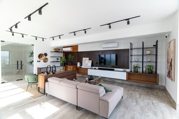 Un soggiorno moderno con un divano, un tavolino e una TV. C'è un'area cucina con un tavolo da pranzo e sedie.