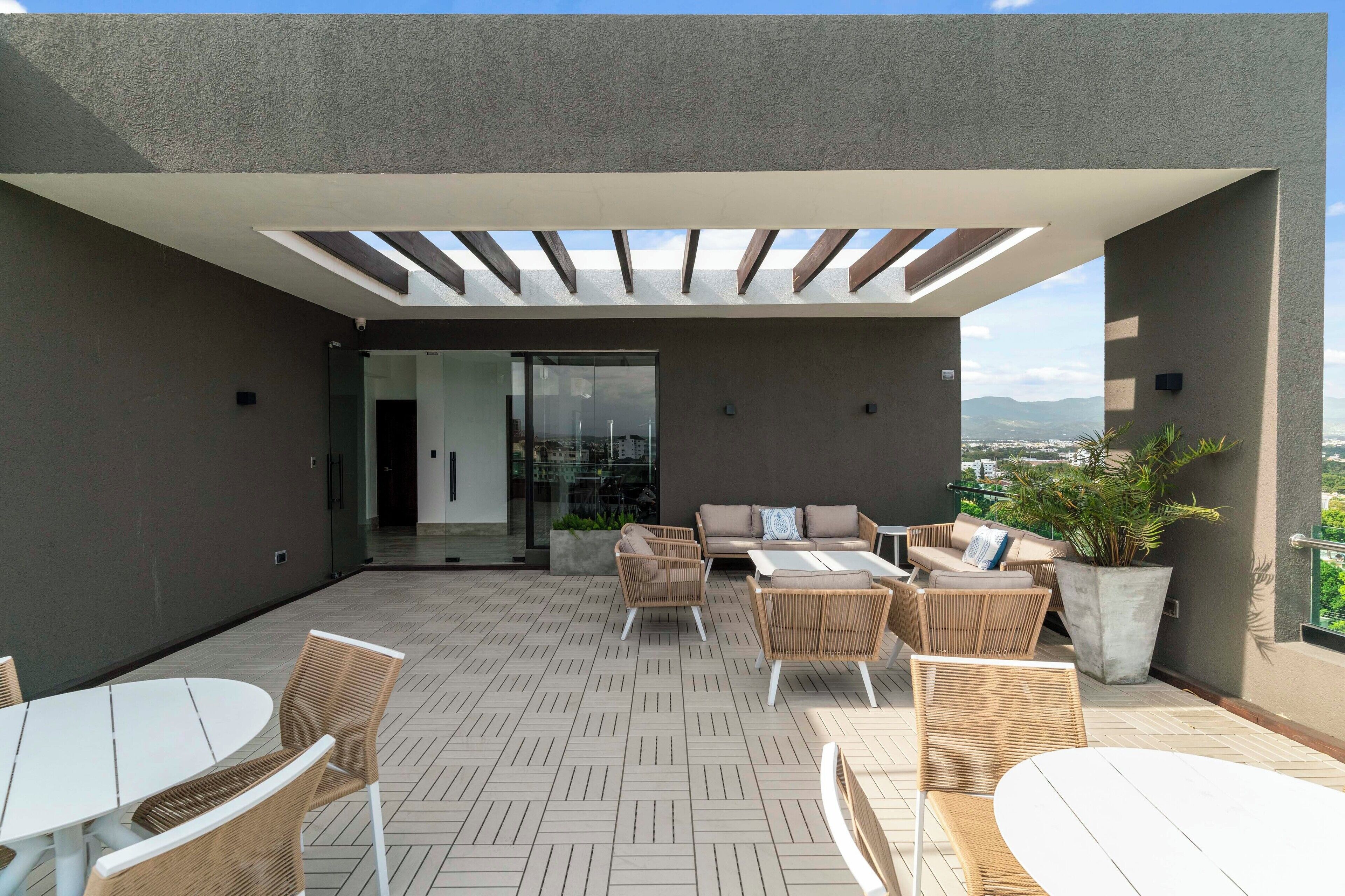 Une terrasse extérieure moderne, dotée d’un espace salon comprenant un canapé et des fauteuils, ainsi qu’une table.