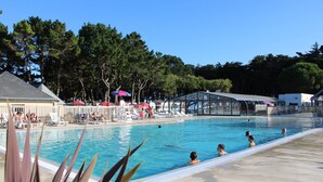 A swimming pool with lounge chairs and umbrellas, surrounded by trees. - "Sunshine-Mbh 61-Sea view-6p (Quiberon)
