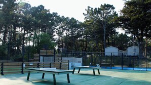 An outdoor tennis court with two benches, surrounded by a fence and trees. - "Sunshine-Mbh 61-Sea view-6p (Quiberon)