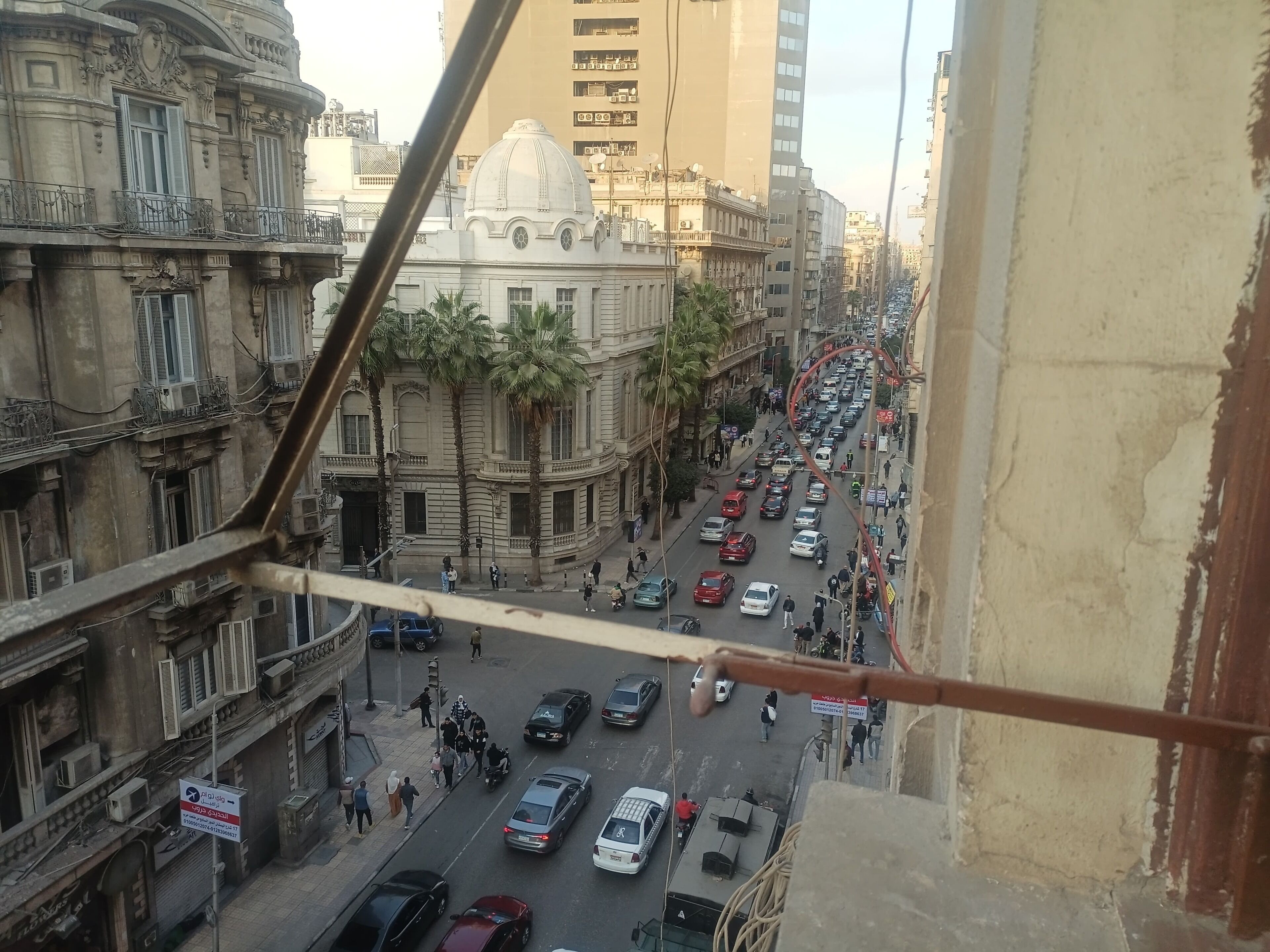 A busy street with cars and pedestrians, historic buildings, and a prominent dome structure.