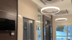A modern lobby with a flat-screen TV, an elevator, and a glass door leading to an outdoor area. - 1BR Covent Garden South Tower University Belt- SM Sta Mesa, Metro Manila,Philippines (Manila)