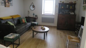 Un salon avec un canapé, une table basse, un fauteuil et une fenêtre.