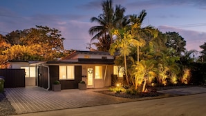 A modern house with a paved driveway, a garage, and a well-lit entrance. - Walk to Wilton Drive - Spacious Quiet Villa 1 (Wilton Manors)