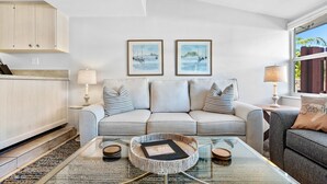 A living room with a sofa, a coffee table, and framed artwork on the wall. - Citrus Isles Waterfront Home (Fort Lauderdale)