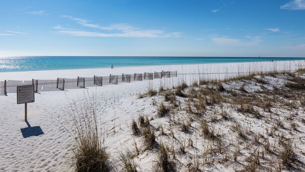 A beach with a wooden fence and a sign indicating beach closure.