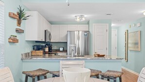 A modern kitchen with white cabinets, stainless steel appliances, and a central island with stools.