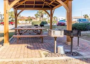 Enjoy outdoor dining and cooking in this gazebo with picnic tables and a grill.