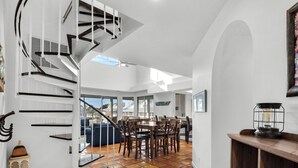 A spacious living area with a spiral staircase, a dining table, and chairs.