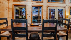 A wooden cabin interior with a dining table and chairs, large windows, and a view of the outside. - *Private Island*w/ free kayaks, hot tub and VIEWS! (Smithville)