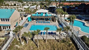 A resort with a large pool, multiple lounge chairs, and a building with a blue roof.