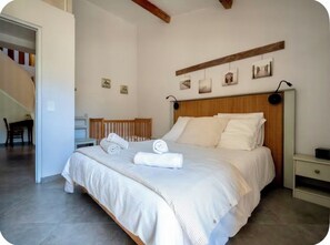 A bedroom with a bed, bedside tables, a wooden headboard, and a staircase leading to another room.