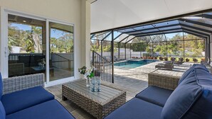 A covered outdoor patio with a pool, seating areas, and a glass door leading to a balcony.