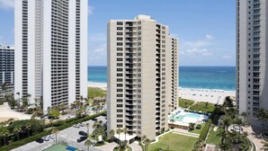 A high-rise hotel with multiple floors, a pool area, and a beach view.