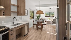 Une cuisine moderne avec des meubles en bois, un évier en acier inoxydable et un coin repas comprenant une table et des chaises.