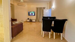 Una sala de estar con un sofá, un televisor y un comedor con sillas.