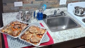 A kitchen with a granite countertop, stainless steel sink, and a stove. There are two aluminum trays with food on the counter. - 069A Private Studio nr South Rim Sleeps 4 (Williams)