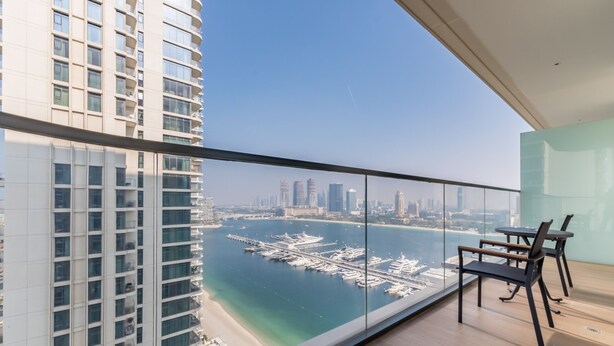 A high-rise apartment with a balcony overlooking a marina and city skyline.