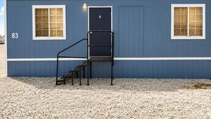 A blue building with a number '83' on the side, a door labeled 'A', and two windows with blinds.