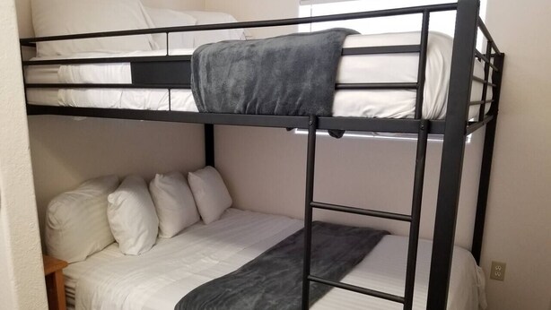 A bunk bed with white bedding and a gray blanket.