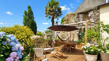 A patio area with a table and chairs, surrounded by potted plants and flowers.