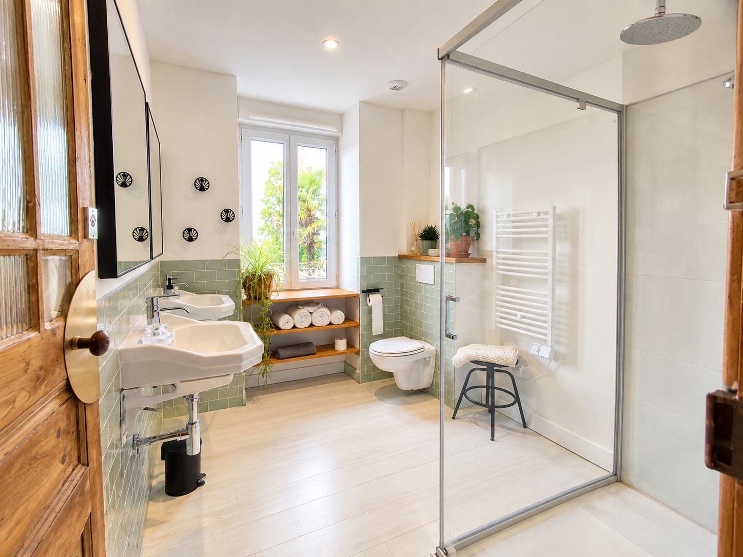 Une salle de bain moderne dotée d’une douche à parois de verre, d’un plancher en bois et d’une fenêtre laissant entrer la lumière naturelle.