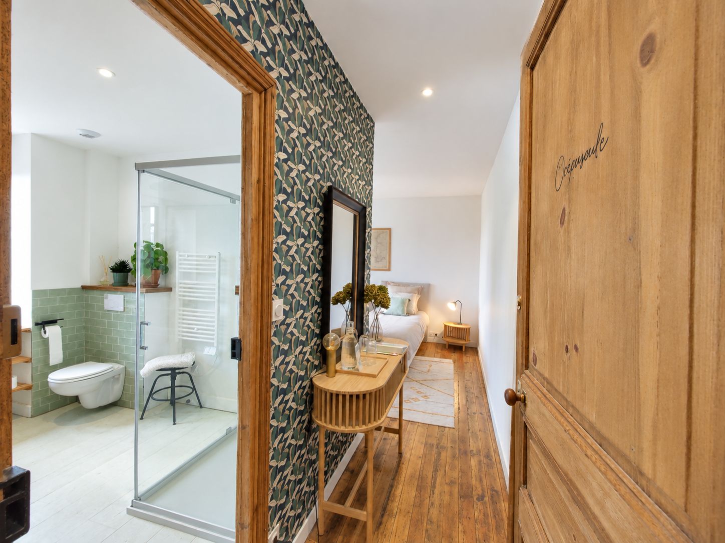 A modern bathroom with a glass shower enclosure, a wooden vanity, and a large mirror.