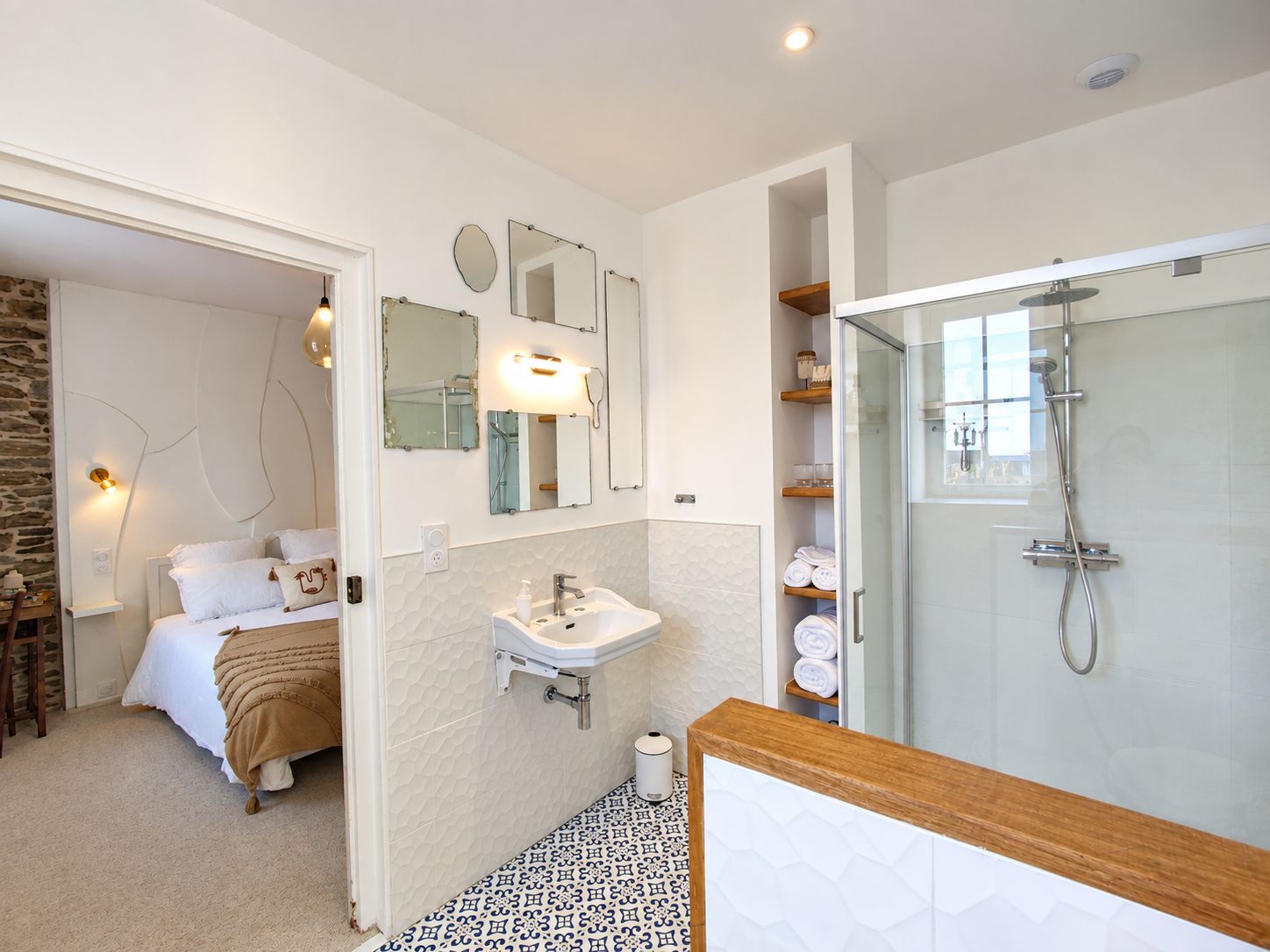 A modern bathroom with a glass shower enclosure, a white sink, and a mirror above it.
