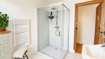 Een moderne badkamer met een douchecabine van glas, een witte wastafel en een houten deur.