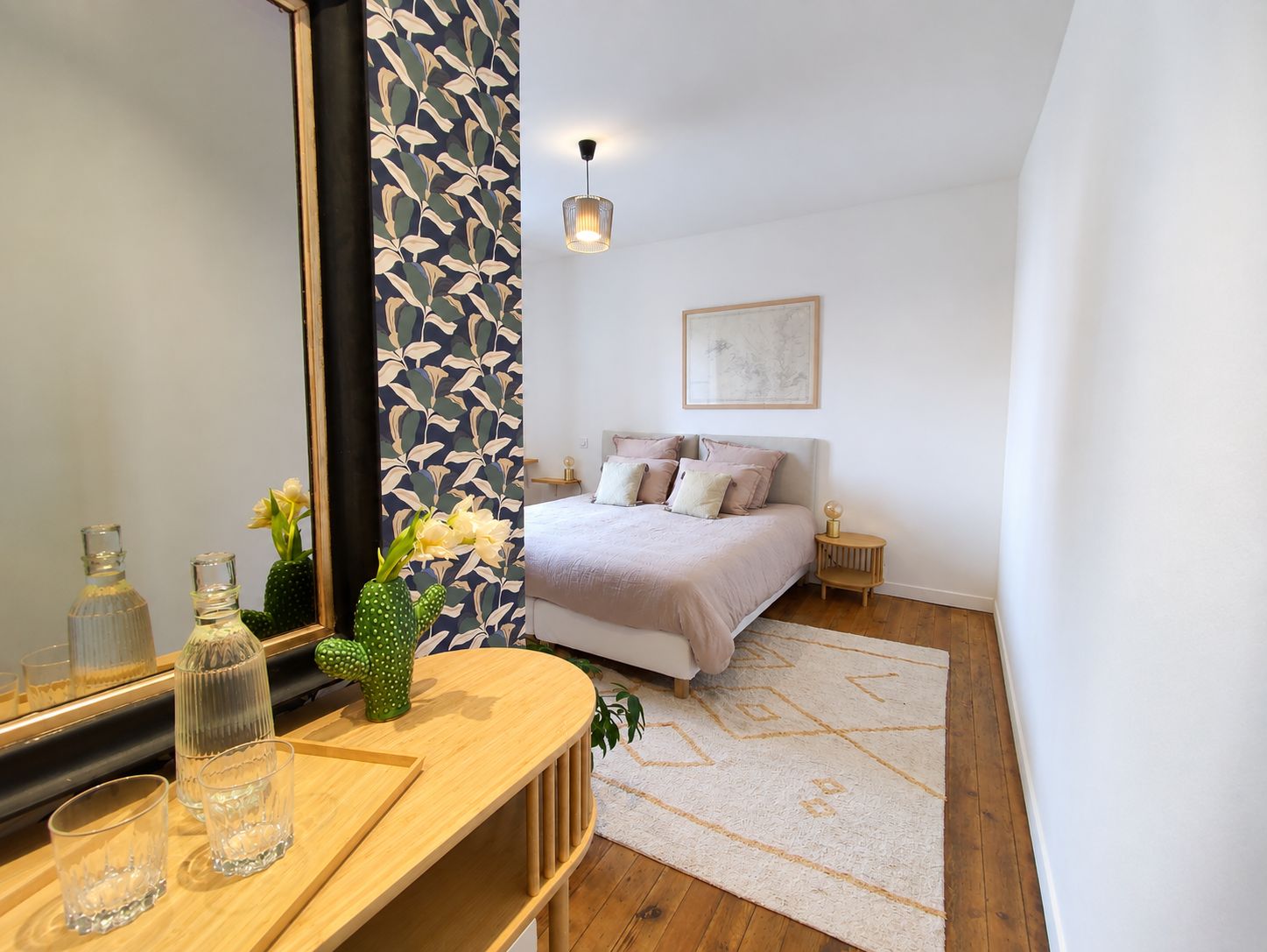 Een slaapkamer met een bed, nachtkastjes, een spiegel en een muur met een bladmotief.