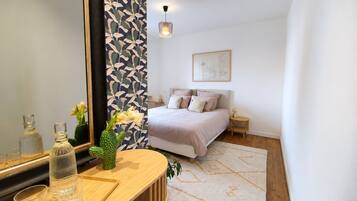 Een slaapkamer met een bed, nachtkastjes, een spiegel en een muur met een bladmotief.