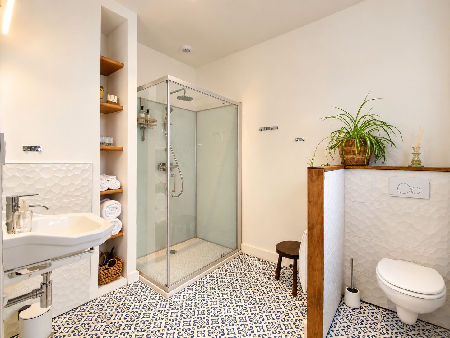 Un baño moderno con ducha envuelta en vidrio, un lavabo con espejo y un inodoro.