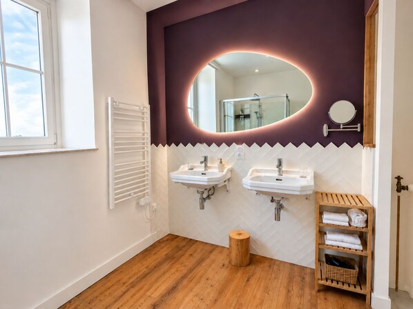 A bathroom with two sinks, a mirror, a wooden stool, and a towel rack. - Les Chambres D'Hespéris (Pleyben)