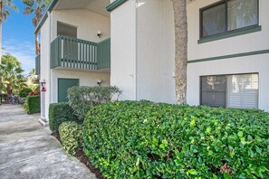 Un bâtiment à deux étages doté d’un balcon verdoyant, d’une haie bien entretenue et surplombant un ciel dégagé.