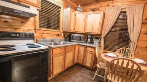 Una cocina con armarios de madera, estufa, microondas y pileta.