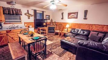 Una sala de estar acogedora con chimenea, televisor y comedor con mesa y sillas de madera.