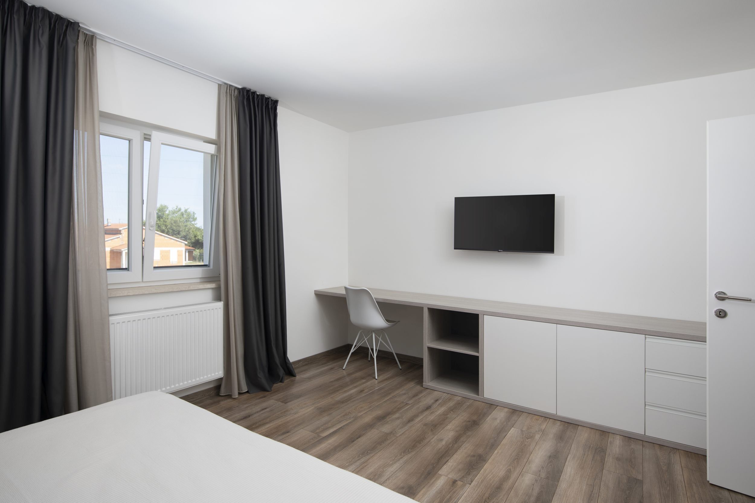 Une chambre à coucher comprenant un lit, un bureau, une chaise, un téléviseur et une armoire.