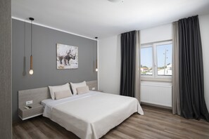Une chambre moderne avec un lit, des tables de chevet, un tableau et une fenêtre avec des rideaux.