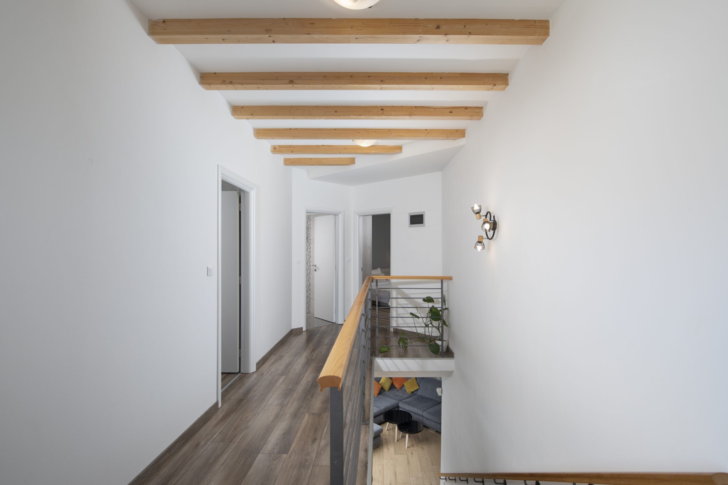 Ein modernes Interieur mit einer Holztreppe, weißen Wänden und einem grauen Sofa.