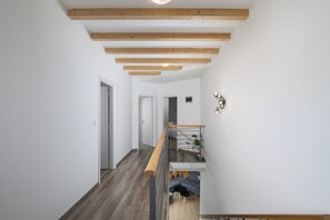 Ein modernes Interieur mit einer Holztreppe, weißen Wänden und einem grauen Sofa.