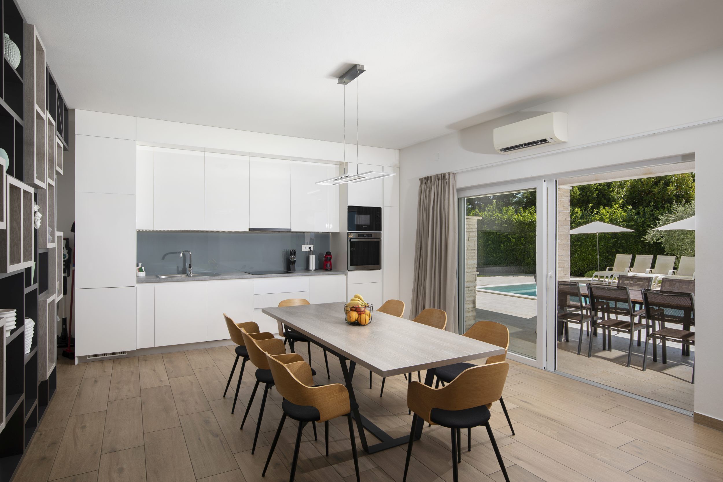 Een moderne keuken met witte kastjes, een houten eettafel en stoelen.