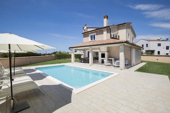 Une maison à deux étages avec une piscine, du mobilier d’extérieur et un espace patio.