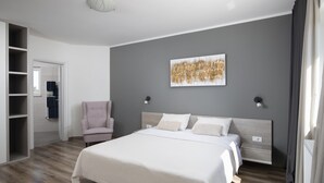 Un dormitorio con una cama, una silla, un armario y un cuadro en la pared.