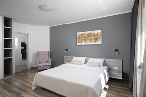 Un dormitorio con una cama, una silla, un armario y un cuadro en la pared.